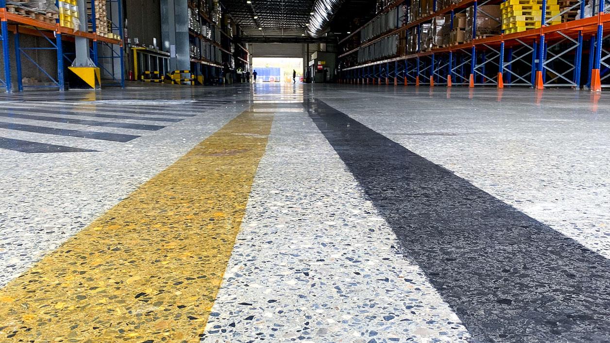 Depo koridorunda parlatılmış beton zemin ve sarı yön çizgisi
